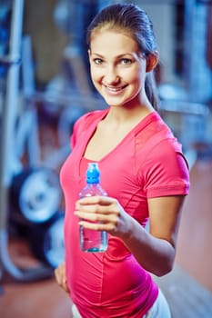Happy young woman with bottle of water looking at camera