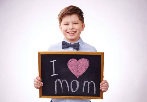 Adorable boy holding board with declaration of love to his mother