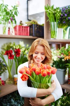 Happy young woman holding vase with fresh tulips