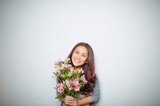 Cheerful female with bunch of pink flowers looking at camera