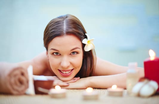 Happy girl with frangipani flower in hair relaxing in spa salon