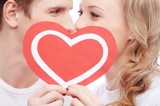 Young people kissing behind paper heart