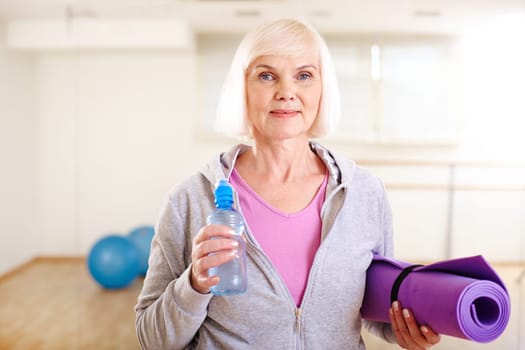 Portrait of aged woman with bottle of water and rug looking at camera