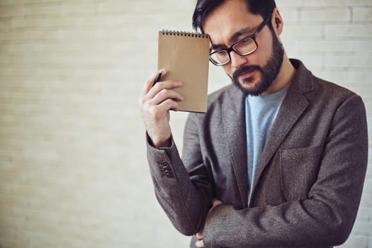 Young businessman with notepad thinking in office