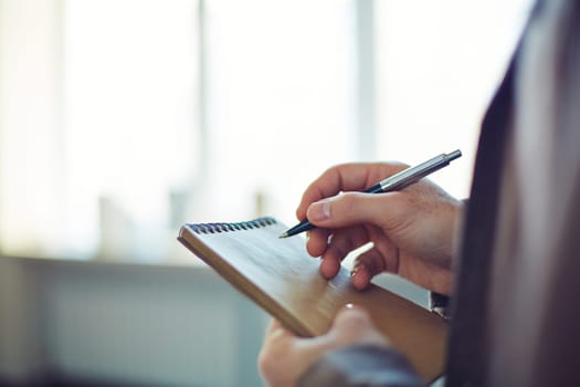 Male hands writing notes with pen in notebook