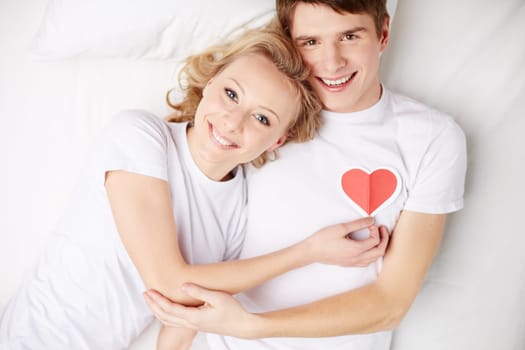 Happy couple lying in bed and looking at camera