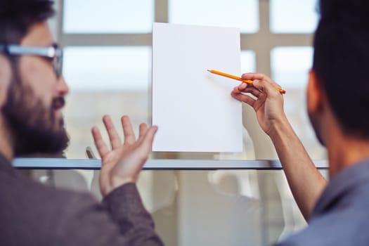 Male manager pointing at blank paper on noticeboard with pencil