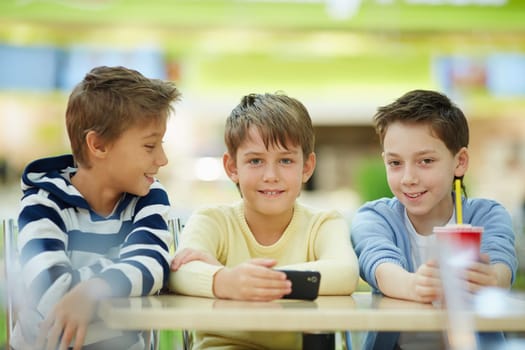 Portrait of three schoolboys sitting at table and looking at camera