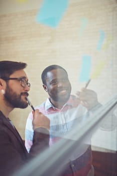 African businessman pointing at reminder while explaining idea to colleague in office