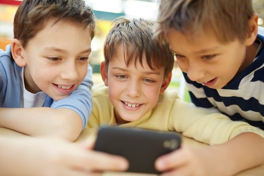 Three happy little boys using cellphone