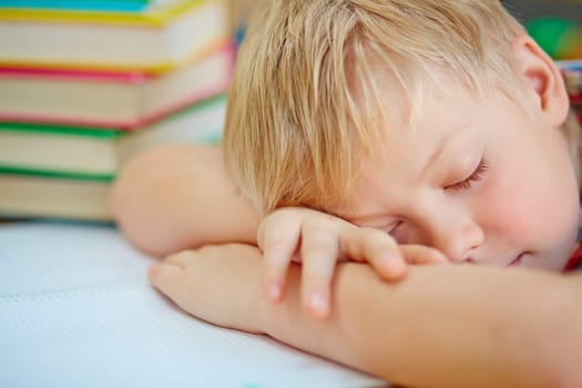 Tired schoolboy napping with head on desk