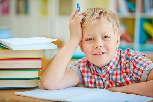 Happy pupil looking at camera by the desk