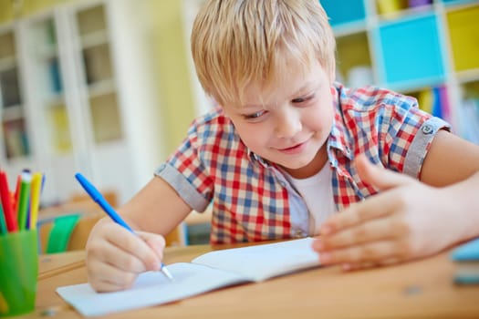 Dishonest schoolboy looking at crib on his palm while writing test