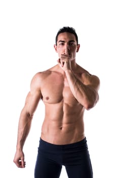 Muscular shirtless young man doing shut up sign with finger on lips