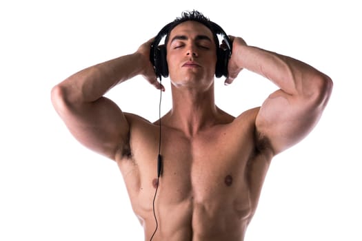 Muscular man shirtless, listening to music on headphones, with eyes closed, isolated