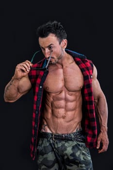 Frontal shot of muscular young man in military pants and open shirt on naked torso