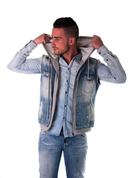 Handsome young man in hoodie, denim vest and jeans, isolated on white
