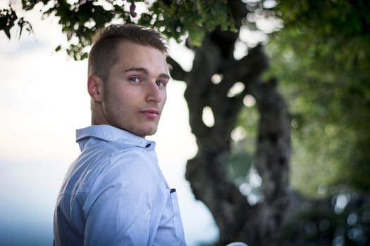 Profile shot of handsome young man outdoors looking at camera
