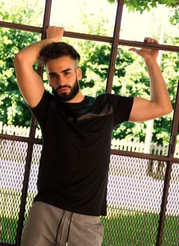 Handsome young man with beard against big metal window frame