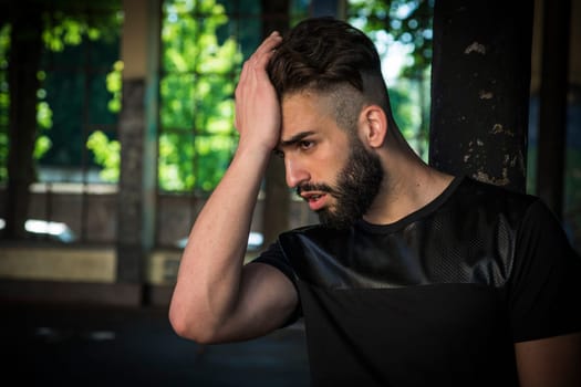 Handsome young man with beard desperate, holding head with hand