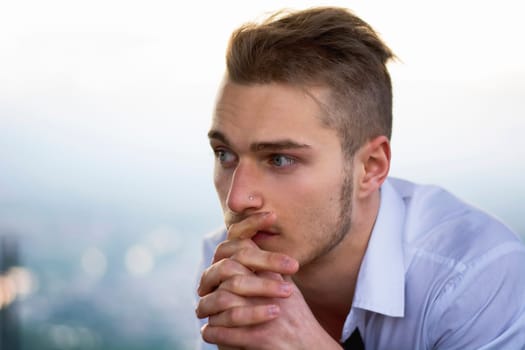 Headshot of serious young man outdoors, looking to a side