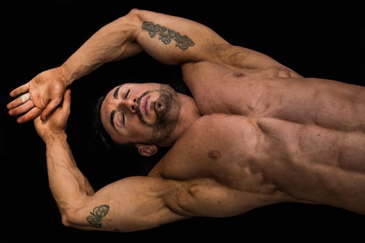 Attractive young muscle man laying on the floor with muscular ripped body