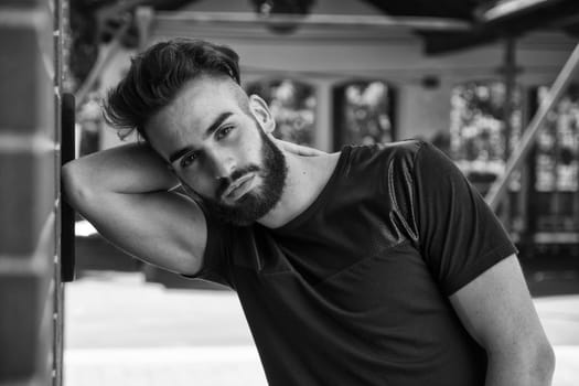 Handsome young man with beard outdoor looking at camera. Black and white shot