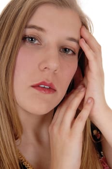 A beautiful young woman with long blond hair looking into the camera.dreaming, with her hand on her face, isolated for white background.