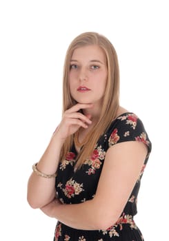 A closeup image of a gorgeous blond woman standing in a dress with.one hand on her chin, isolated for white background.