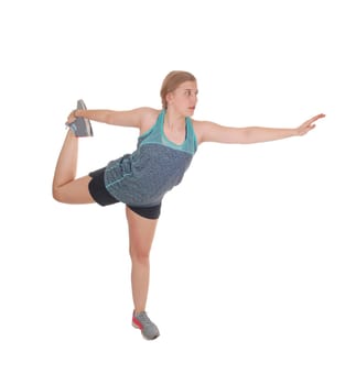 A young pretty woman standing isolated for white background .stretching her body with one leg up and outstretched arm.