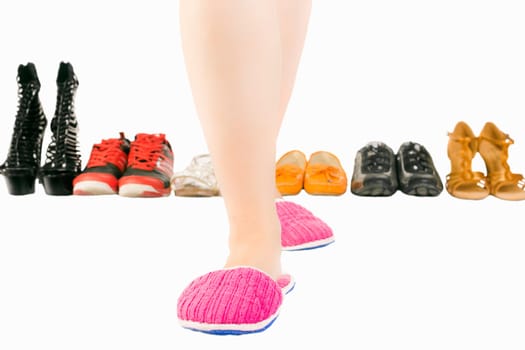 Female legs in pink slippers on white background with different shoes and footwear.