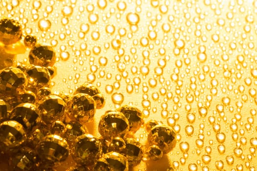 Shiny golden pearls are on golden background with water drops.