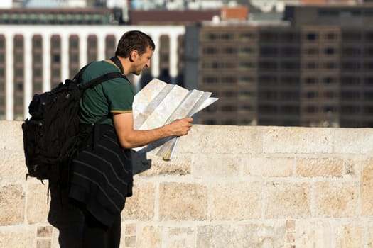 The tourist is looking at the map in the city and looking for his destination.