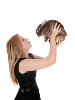 A lovely young blond woman standing in profile close up and holding up.a young bunny, isolated for white background.