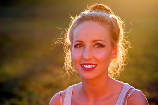 Portrait about a smiling young woman at sunset.