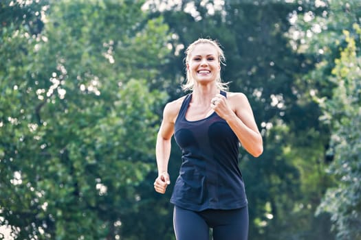 Blonde young woman running in the park