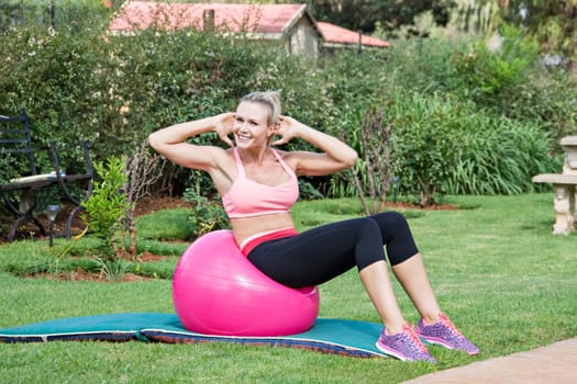 Blonde young woman exercising pilates with the ball at home
