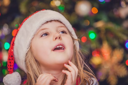 Cute Christmas girl with the Christmas tree lights bokeh in the background