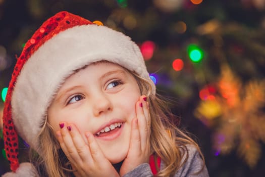 Cute Christmas girl with the Christmas tree lights bokeh in the background