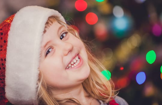 Cute Christmas girl with the Christmas tree lights bokeh in the background