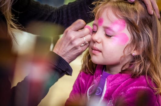 Little girl having her face painted during party