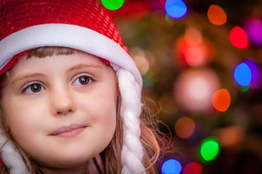 Cute Christmas girl with the Christmas tree lights bokeh in the background