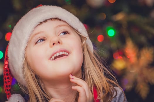 Cute Christmas girl with the Christmas tree lights bokeh in the background