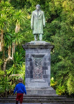 Little boy under the sculpture in the José do Canto Botanical Garden in Ponta Delgada, the capital of Sao Miguel island, Azores, Portugal