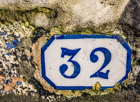 Old door plaque with the number 32 on a wall of an old home