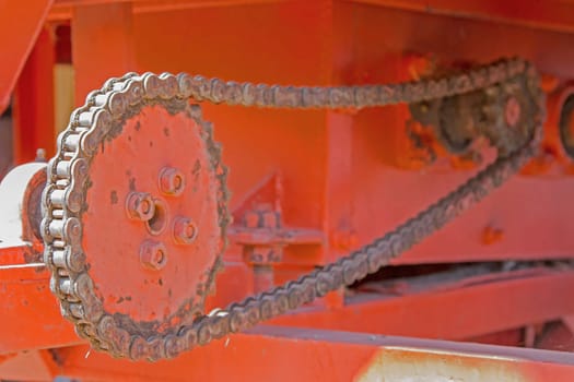 Chains and gear wheels in agricultural machinery and  orange background