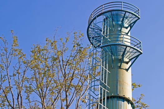 Water tower and blue sky  is near tree