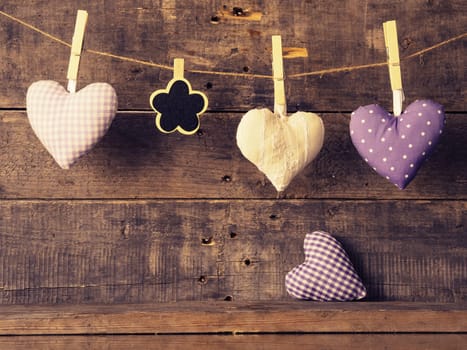 Three fabric heart shapes with a small flower shaped chalkboard on a wooden wall, Valentines Day or Mothers Day concept
