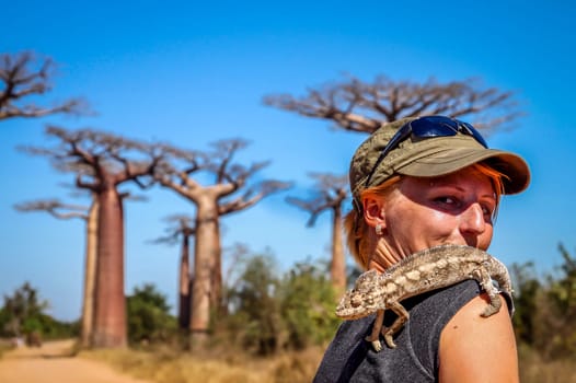 Girl and chameleon in the Avenida de Baobab in Madagascar