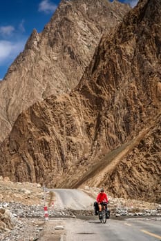 Solo female cyclist on the bicycle on the stunning remote road in Xinjang province leading to Western Tibet